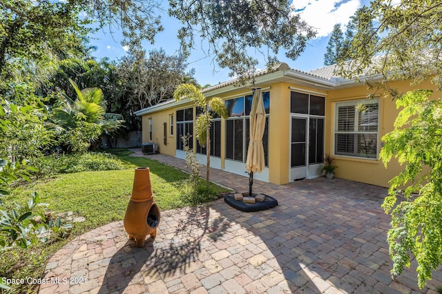 back of property featuring a yard, a patio area, and a sunroom