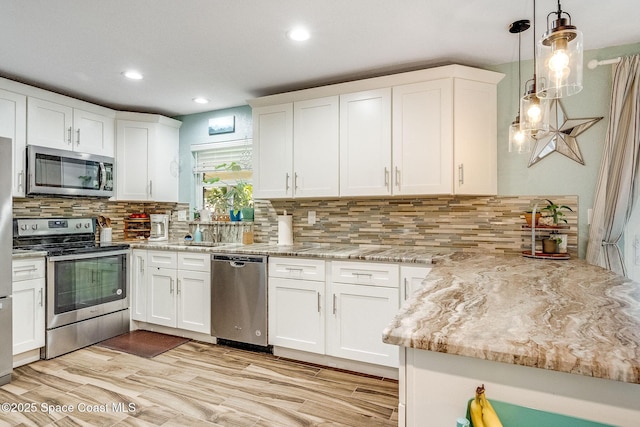 kitchen featuring stainless steel appliances, white cabinetry, hanging light fixtures, and decorative backsplash