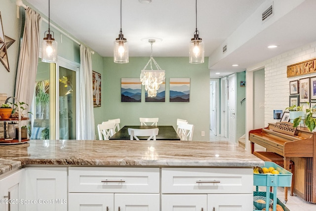 kitchen featuring white cabinetry, hanging light fixtures, and light stone countertops