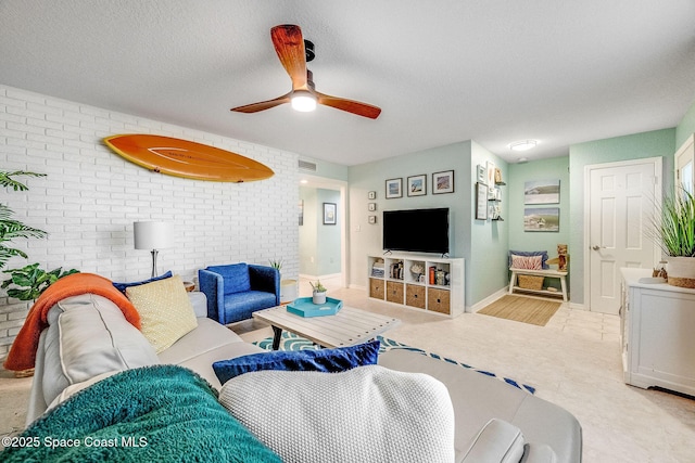 tiled living room with ceiling fan, brick wall, and a textured ceiling