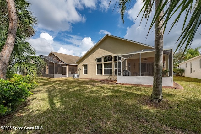 rear view of property featuring cooling unit, a lawn, ceiling fan, and glass enclosure