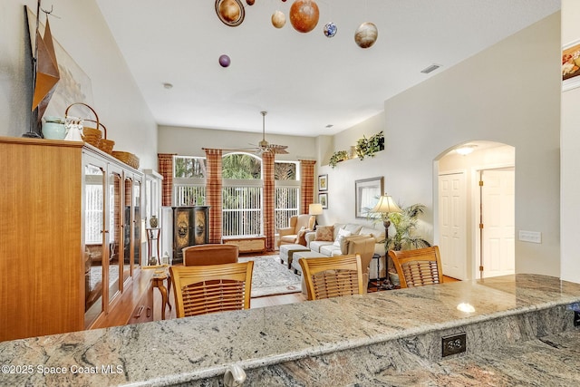 kitchen with hardwood / wood-style flooring, light stone countertops, and ceiling fan