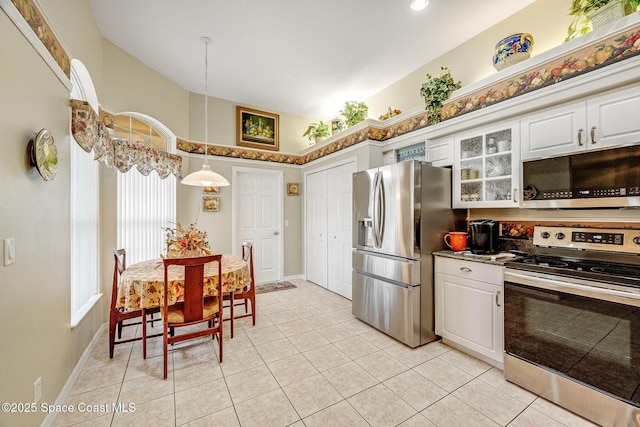 kitchen with white cabinetry, lofted ceiling, stainless steel appliances, and decorative light fixtures