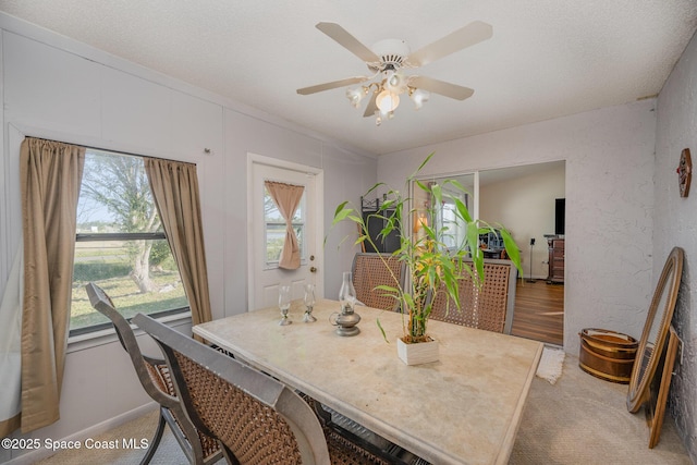 dining space with light carpet, ceiling fan, and a textured ceiling