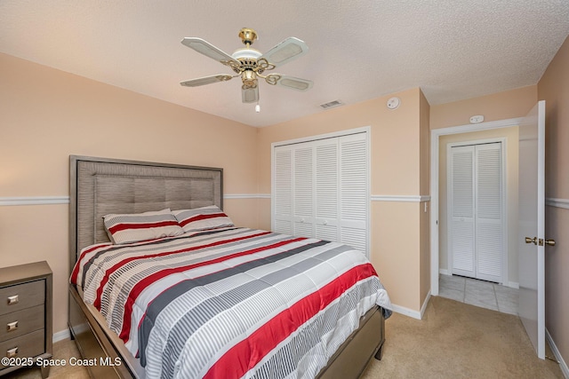 carpeted bedroom with a textured ceiling, ceiling fan, and a closet