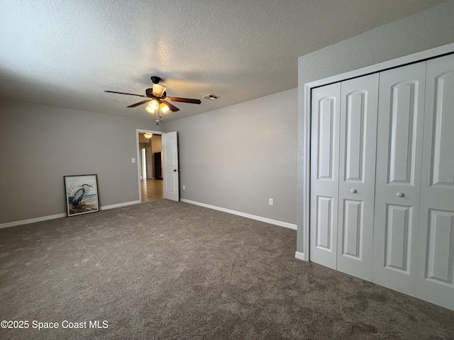 unfurnished bedroom with ceiling fan, dark carpet, a closet, and a textured ceiling