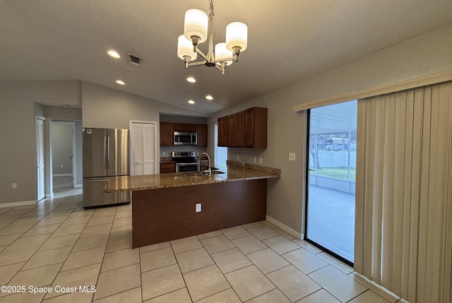 kitchen featuring appliances with stainless steel finishes, pendant lighting, lofted ceiling, kitchen peninsula, and a textured ceiling