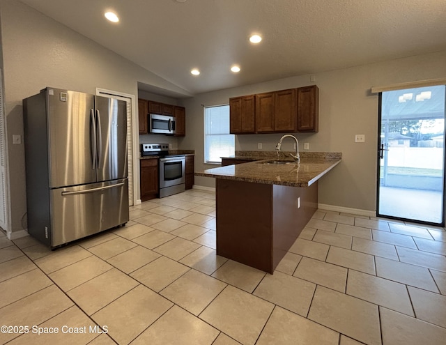 kitchen featuring lofted ceiling, sink, appliances with stainless steel finishes, dark stone countertops, and kitchen peninsula