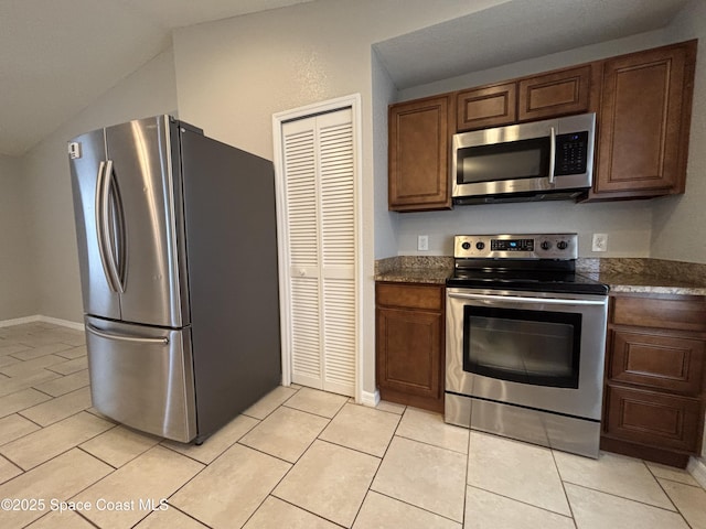 kitchen featuring light tile patterned floors, vaulted ceiling, and stainless steel appliances