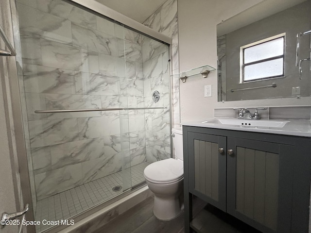 bathroom with vanity, toilet, and a shower with door