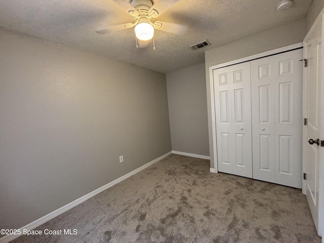 unfurnished bedroom with light carpet, a textured ceiling, a closet, and ceiling fan