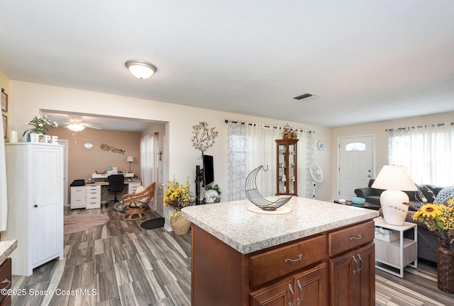 kitchen featuring ceiling fan, wood-type flooring, a kitchen island, and a textured ceiling