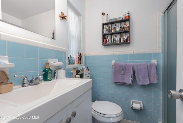 bathroom with vanity, a shower with shower door, tile walls, and toilet