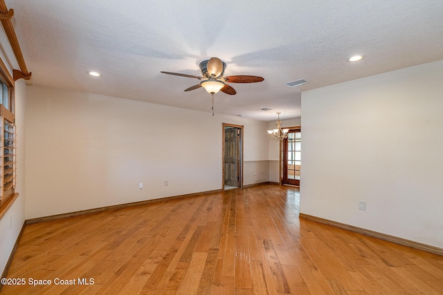 unfurnished room featuring ceiling fan with notable chandelier, a textured ceiling, and light wood-type flooring