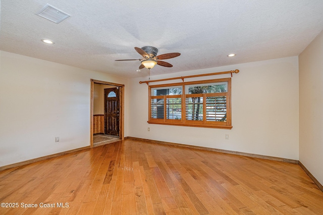 empty room with ceiling fan, a textured ceiling, and light wood-type flooring