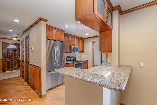 kitchen featuring light stone counters, crown molding, kitchen peninsula, stainless steel appliances, and light hardwood / wood-style floors