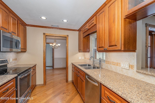 kitchen featuring sink, light stone counters, light hardwood / wood-style flooring, appliances with stainless steel finishes, and backsplash