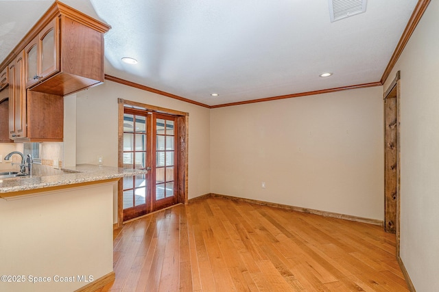 interior space with ornamental molding, sink, light hardwood / wood-style flooring, and french doors