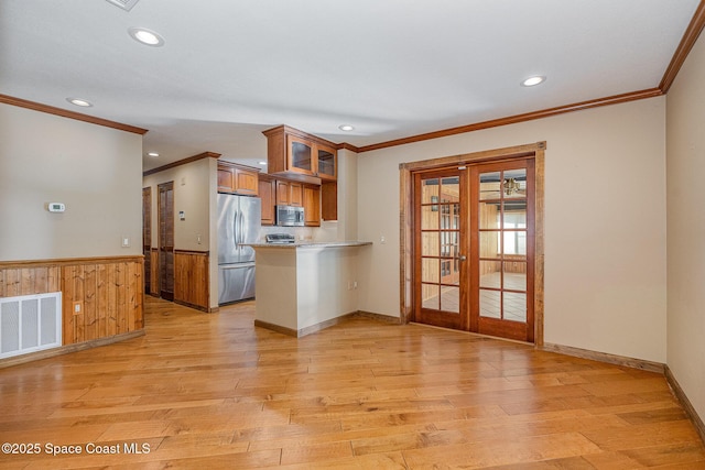 kitchen with light wood-type flooring, stainless steel appliances, kitchen peninsula, and french doors