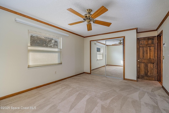 unfurnished bedroom with light colored carpet, ornamental molding, a closet, and a textured ceiling