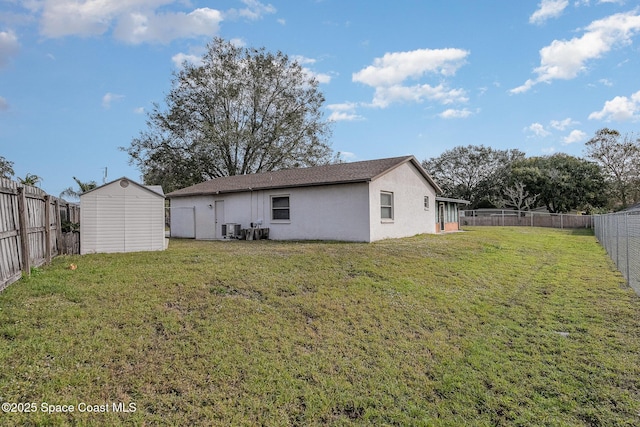 rear view of house featuring a lawn, central AC unit, and a shed