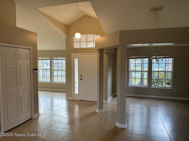 tiled foyer entrance with lofted ceiling and a textured ceiling