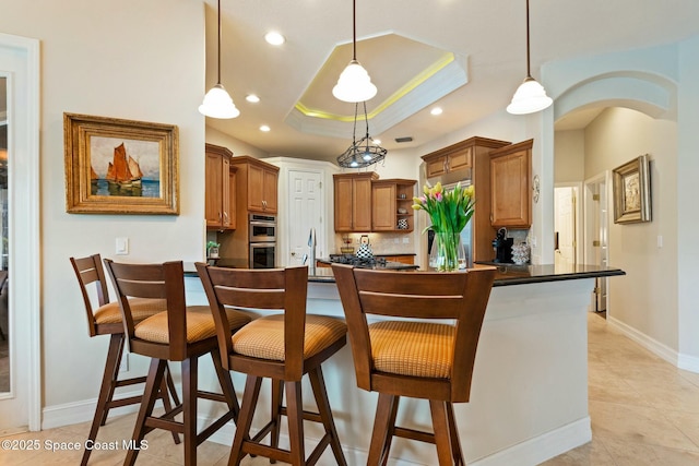 1459 Southpointe Ct, Melbourne, FL 32940 - kitchen with a breakfast bar, dark countertops, a raised ceiling, open shelves, and double oven
