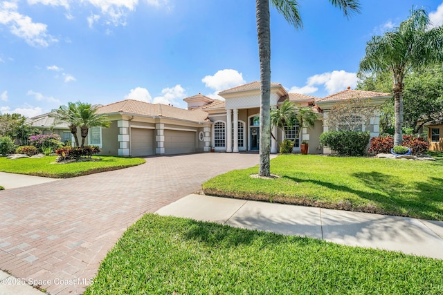 1459 Southpointe Ct, Melbourne, FL 32940 - mediterranean / spanish home featuring decorative driveway, a garage, a tile roof, a front lawn, and stucco siding