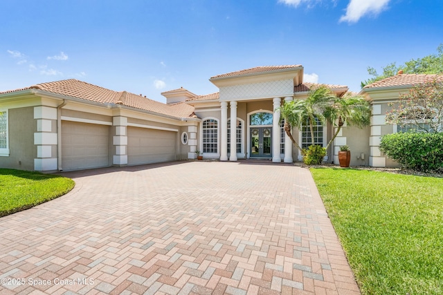 1459 Southpointe Ct, Melbourne, FL 32940 - mediterranean / spanish-style home featuring a tiled roof, decorative driveway, a garage, stucco siding, and french doors