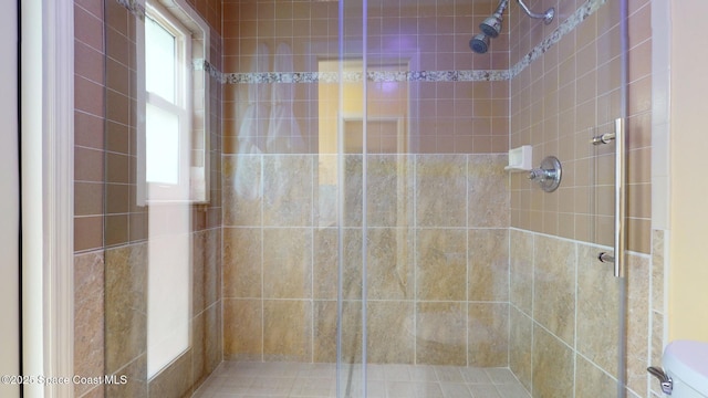 bathroom with a shower with door and toilet