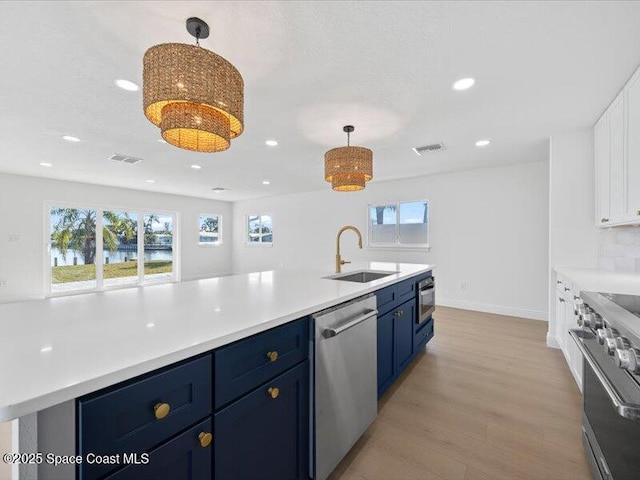 kitchen with sink, decorative light fixtures, stainless steel appliances, and blue cabinets