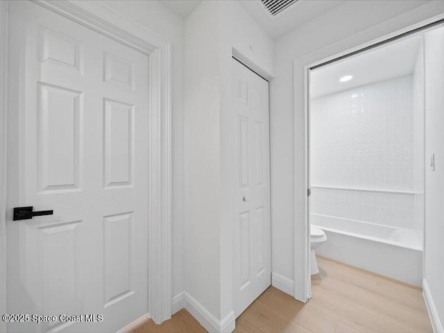 interior space featuring shower / tub combination, wood-type flooring, and toilet