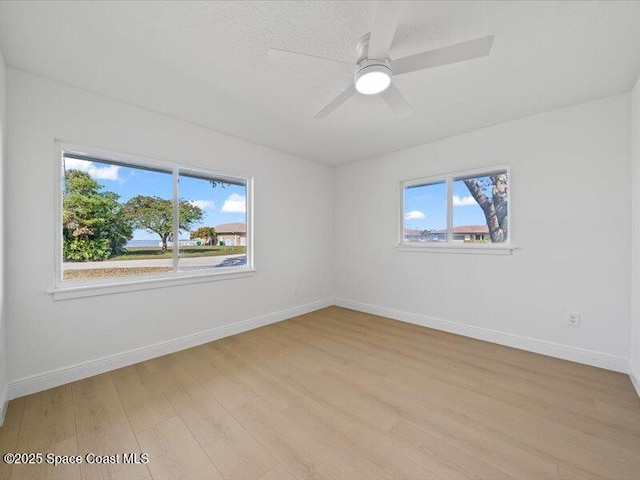 spare room with ceiling fan, a healthy amount of sunlight, and light hardwood / wood-style floors