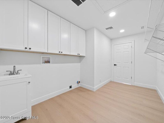 clothes washing area featuring cabinets, light hardwood / wood-style floors, hookup for a washing machine, and electric dryer hookup