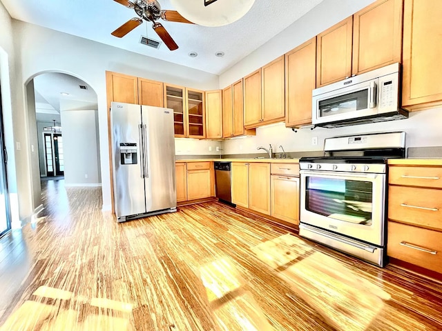 kitchen with ceiling fan, appliances with stainless steel finishes, sink, and light hardwood / wood-style floors