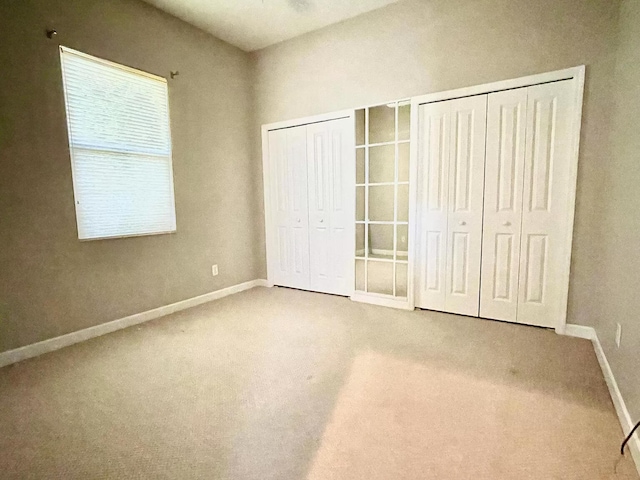 unfurnished bedroom with carpet floors and two closets