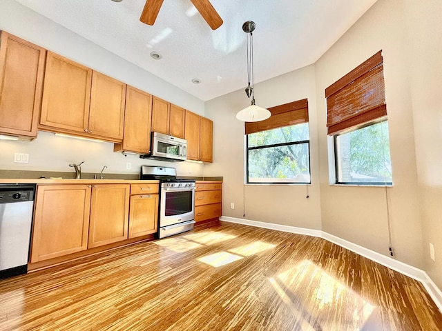 kitchen featuring stainless steel appliances, decorative light fixtures, light hardwood / wood-style floors, and sink