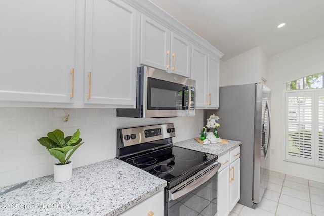 kitchen with backsplash, stainless steel appliances, light stone counters, white cabinets, and light tile patterned flooring