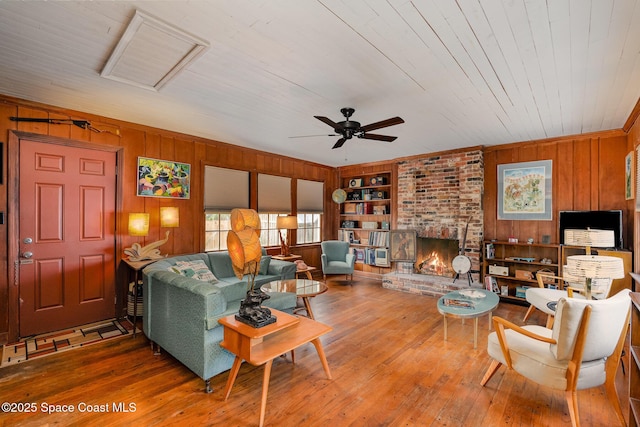 living room with hardwood / wood-style floors, wooden walls, a brick fireplace, wooden ceiling, and built in shelves