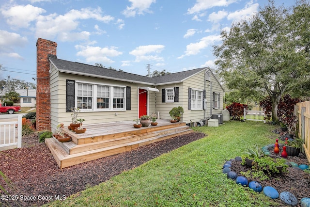 single story home featuring cooling unit, a wooden deck, and a front lawn