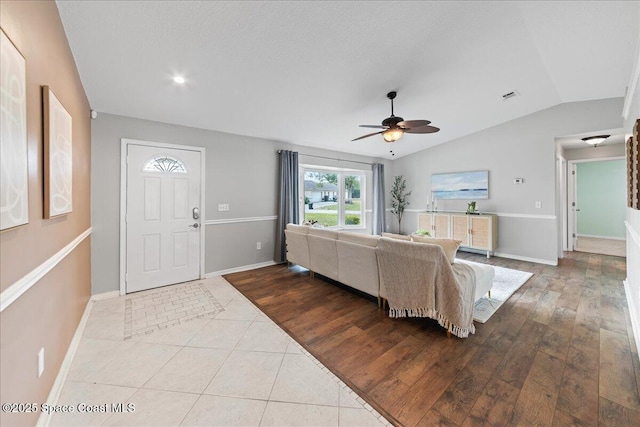 living room featuring lofted ceiling, a textured ceiling, ceiling fan, and light hardwood / wood-style flooring