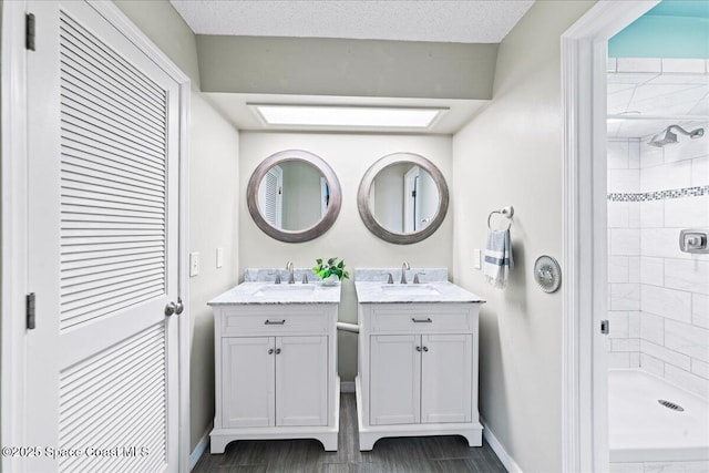 bathroom featuring vanity, a tile shower, and a textured ceiling