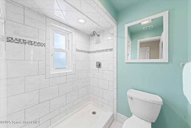 bathroom with a tile shower and toilet