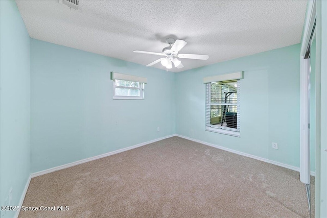 unfurnished room with ceiling fan, plenty of natural light, light colored carpet, and a textured ceiling