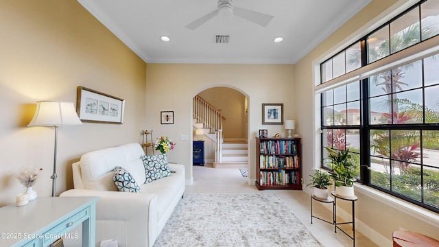 living area with visible vents, baseboards, arched walkways, ornamental molding, and stairs