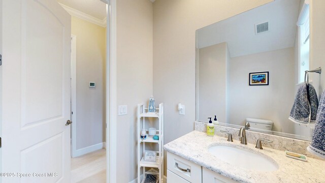 half bathroom featuring visible vents, baseboards, toilet, and vanity