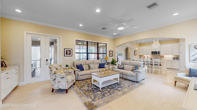 living room with recessed lighting, visible vents, arched walkways, and crown molding