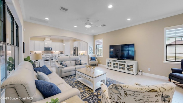 living area with recessed lighting, arched walkways, visible vents, and ornamental molding