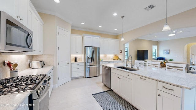 kitchen featuring white cabinets, arched walkways, appliances with stainless steel finishes, and a sink