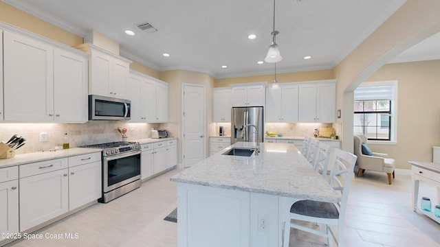 kitchen with visible vents, a sink, stainless steel appliances, a breakfast bar area, and white cabinets